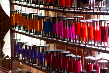 Different colourful reels of cotton stacked upright and ready to use at a tapestry factory. © Migara