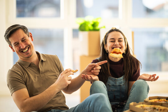 Couple enjoys pizza and cookies while sitting on the floor in their home during a fun moment together