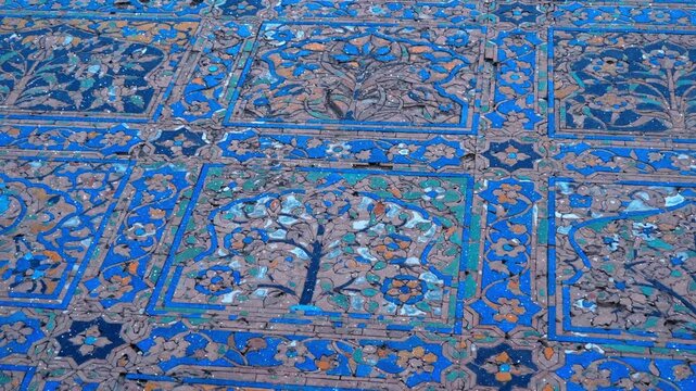 Colorful blue mosaics with floral patterns in Mughal style depicted on the wall of a Mosque in the Taj Mahal complex, Agra, Uttar Pradesh, Indi. View through sparkling particles. Shot in motion