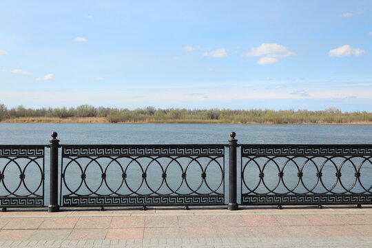openwork cast-iron casting on the embankment, sunny day, far shore,