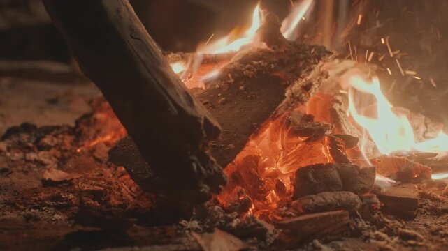 Roaring campfire with burning logs, intense orange flames and popping embers, camping group cooking over firepit with skillet and marshmallow, warm communal glow, loud crackle and cinematic night