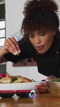 Vertical video: Chef reaching to steady plate salting food to serve while eco icons showing CO2