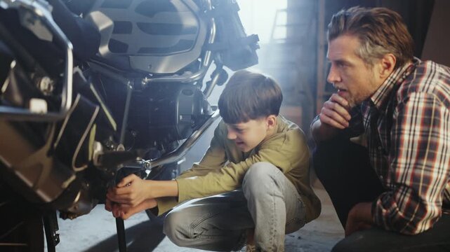 A father and son are fixing a motorcycle in a garage. They are focused on repairing parts and sharing tools. It is a sunny afternoon with natural light coming in.