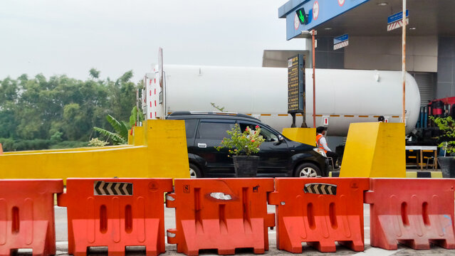 Toll gate with orange barriers and vehicles passing. Highway traffic and transportation system concept.
