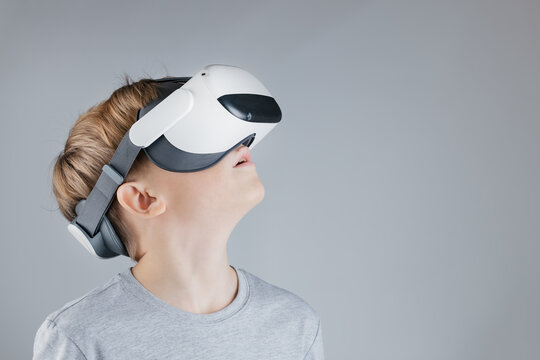 Enthusiastic Boy Discovering Metaverse with VR Headset and Dual Controllers, Dynamic Pose on Minimalist Gray Background