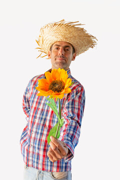 Man dressed for the June festivals in Brazil offering a flower