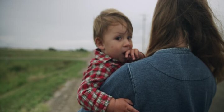 Mother carrying a toddler down a country road