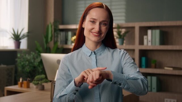 Smiling Caucasian business woman pointing at wristwatch reminding about meeting time office female manager punctual businesswoman employer girl checking clock deadline schedule appointment timing work