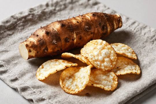 A close-up of a sweet potato next to a pile of crackers on a linen napkin, organic cassava root to chip storytelling photography