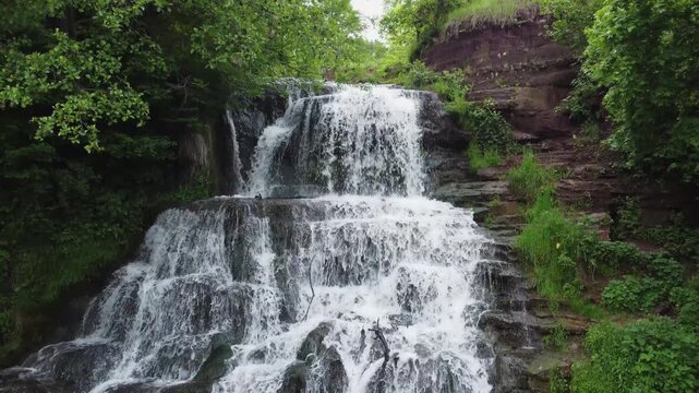 Cascade waterfall among the trees in spring overcast day