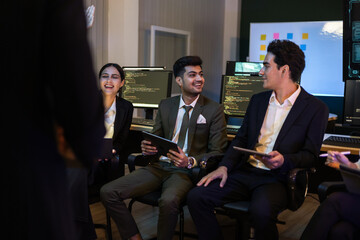 Team of developers and business people using tablets and computers in dark office lab. Diverse...