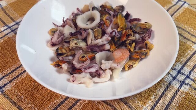 Mix of boiled seafoods in white bowl on checkered napkin