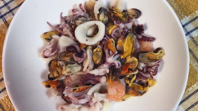 Mix of boiled seafoods in white bowl on checkered napkin