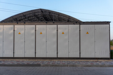Fototapeta premium Utility Boxes Located Near a Large Metal Structure in an Urban Area During Late Afternoon With Clear Skies