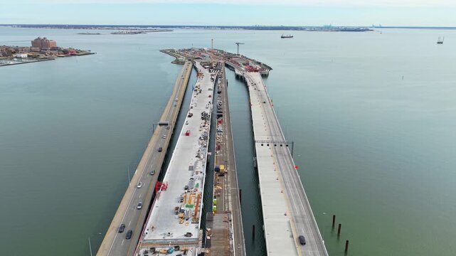 Aerial video of the Hampton Roads Bridge-Tunnel expansion project in Virginia, showing highway bridge construction, heavy cranes, and traffic over the Chesapeake Bay.