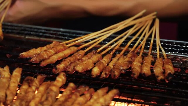 Chicken satay grilled on burning charcoal and fire. Traditional satay is street food from Indonesia. Chicken satay on traditional charcoal fire. satay on fire with smoke.