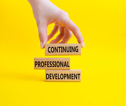 Continuing Development symbol. Concept words Continuing Professional Development on wooden blocks. Businessman hand. Beautiful yellow background. Business and Development concept. Copy space