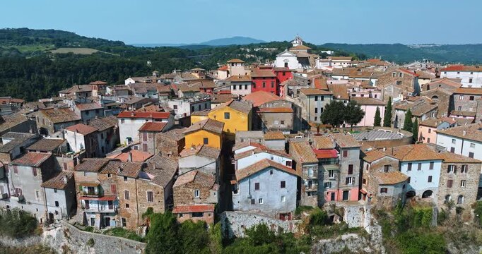 Cinematic drone flight Orte panorama Lazio region. Medieval masonry architecture buildings cliff forest valley backdrop. Italian culture summer trip destination. Tiled roofs ancient town background.