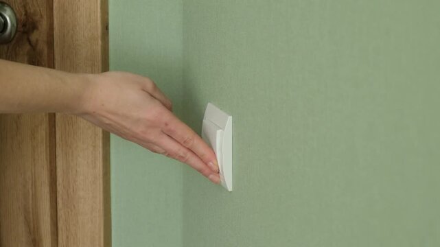 Paranoid woman with agoraphobia turning off the light switch and hiding behind the door in her home, feeling afraid and looking up anxiously at a potential threat or strange noise