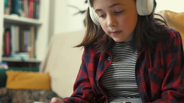  Responsible preteen girl in headphones using tablet to learn about houseplant care at home - 4k, 10bit footage.