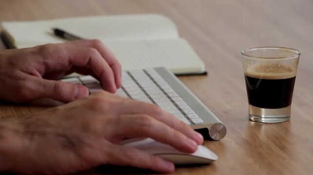 Close-Up of Hands Typing on Keyboard with morning coffee on the table