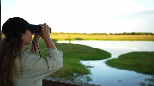 Female birdwatcher observing wildlife with binoculars