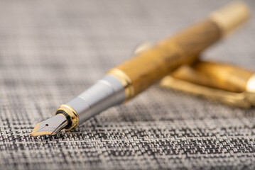 Fototapeta premium Fountain pen, beautiful fountain pen with details on a rustic surface with braided wires, selective focus.