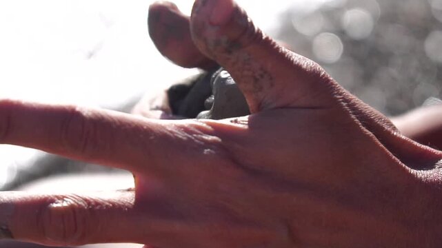 Hands, clay, molding close-up of human hands sculpting wet clay outdoors on a sunny day