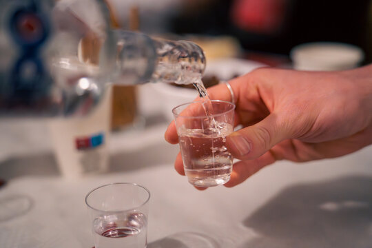 Pouring a shot of vodka or schnapps into a plastic cup at a party or social gathering