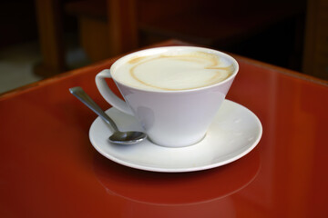 Obraz premium A cup of coffee with foam on a red table