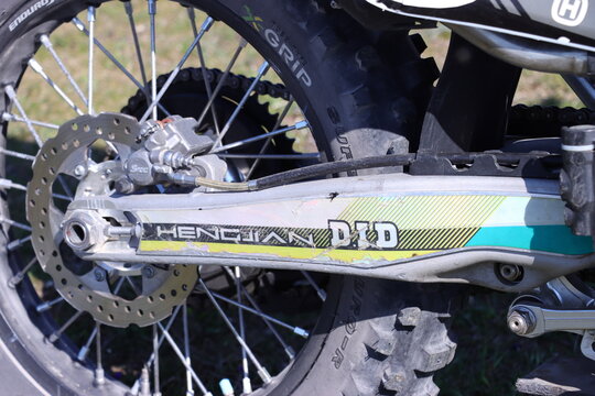 Rear wheel detail of dirt bike with disc brake system. Off-road motorcycle swingarm mechanism. Extreme sport machinery and enduro gear. Automotive maintenance and mechanical engineering.