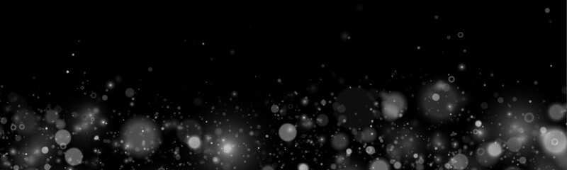 Shimmering white dust sparkles float softly across a dark scene. Tiny particles drift gracefully in motion. Perfect overlay for Christmas, New Year, and festive designs. © goldstock