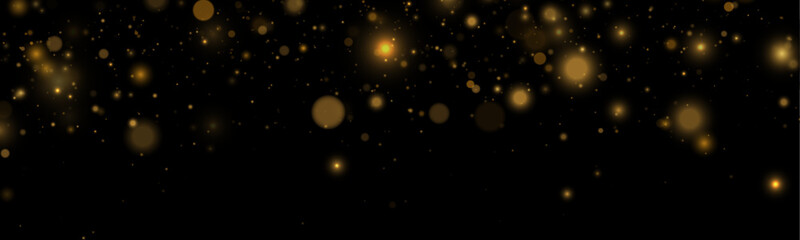 Golden glitter dust glows softly with radiant highlights on a dark background. Tiny sparkling particles drift gracefully. Perfect overlay for holiday and festive designs. © goldstock