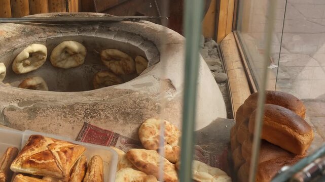Baker hands fresh flatbreads in bag to customer at street bakery window. Baking and selling bread products in busy city location. Traditional Middle Eastern bakery with authentic baked goods