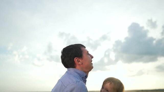 Father joyfully throws child air. Happy family bonding fun outdoors. Child laughing as father throws air. Playful family moment nature. Fun family playtime throwing child. Child flying air fun family.