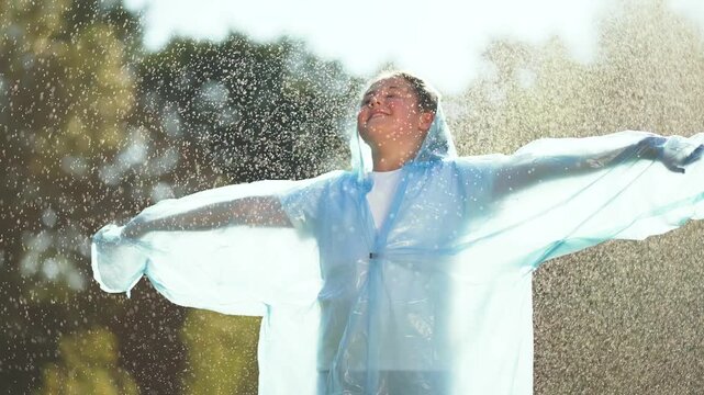 Happy child play in rain. Raincoat clad child enjoying rain. Happy moments in nature. Happy Child laughter raincoat raindrops. Carefree playtime. Rain child raincoat joy. Fun filled rainy day outdoors