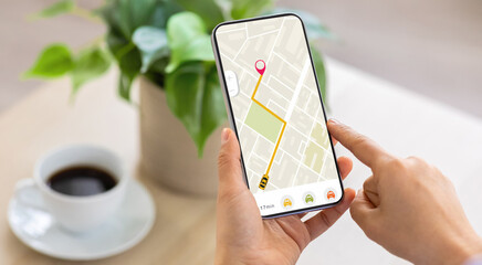 Naklejka na ściany i meble Cropped of woman using navigation mobile app on smartphone, using tracking service, order taxi online. Unrecognizable lady drinking coffee at home, waiting for cab, panorama