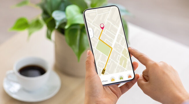 Cropped of woman using navigation mobile app on smartphone, using tracking service, order taxi online. Unrecognizable lady drinking coffee at home, waiting for cab, panorama