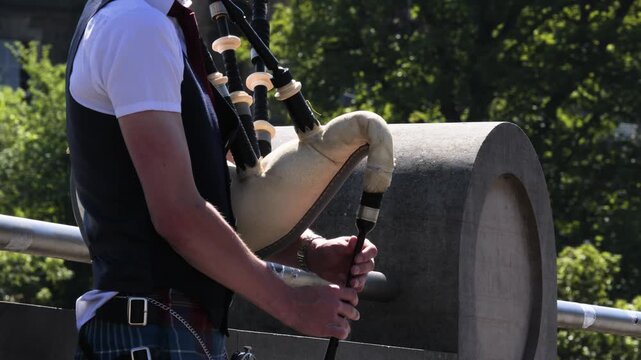 Traditional Scottish Musician in Kilt Playing Bagpipes Outdoors