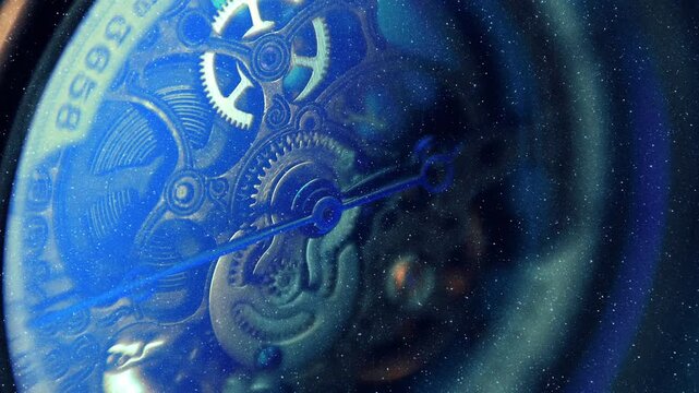 Beautiful internal structure of a skeleton wristwatch where shiny gears, wheels and hands move with bright bokeh. View through sparkling particles. Closeup. Macro. Shallow depth of field