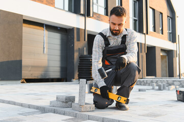 Construction worker laying paving stones using level tool