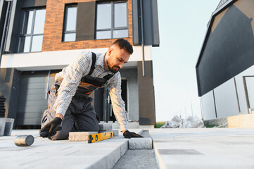 Construction worker laying paving stones around new house