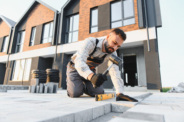 Man worker installing paving stone on building site