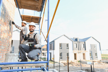 Construction workers plastering wall on building site