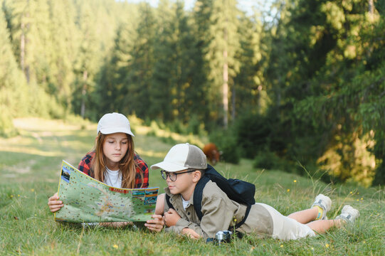 Young explorers studying map during hiking adventure in forest