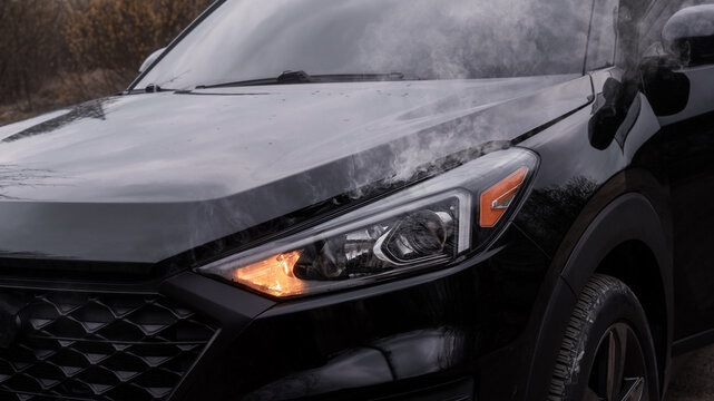 broken black modern car. smoke from under the hood, emergency stop, repair, problem