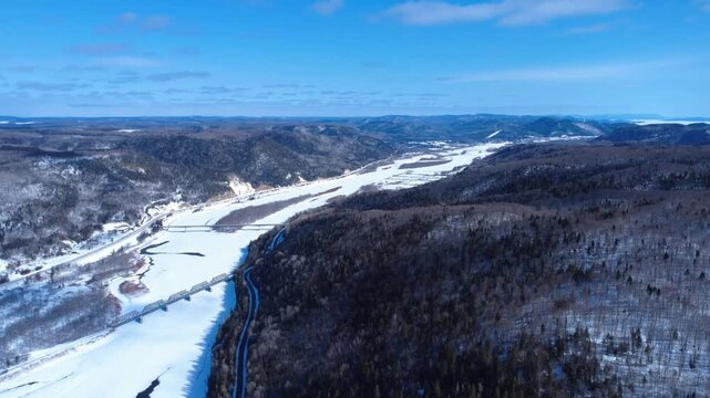 Drone view from high altitude of the frozen Restigouche Salmon River. This historic waterway forms the natural border between Quebec's Gaspe Peninsula and New Brunswick, Canada, in winter.