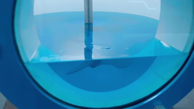 A laboratory glass mixer uses an impeller to stir black particles in a liquid. Closeup