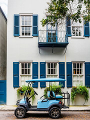 Golf cart parked in front of historic house with blue shutters and balcony in Charleston, SC © Katia