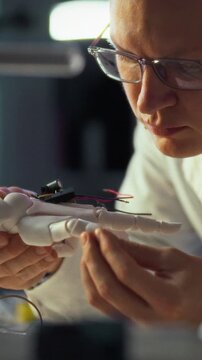 In high-tech lab buzzing with monitors and tools, engineer carefully assembles robotic arm prototype, wiring components and calibrating joints. precise assembly work drives innovation in automation